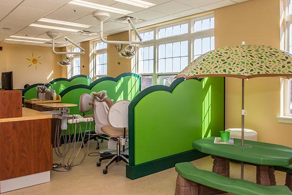 Interior of Dental Office - dental chair areas are separated with fun green panels that resemble lily pads. There is also a child-size picnic table that blends in with the green, outdoorsy theme of the interior.