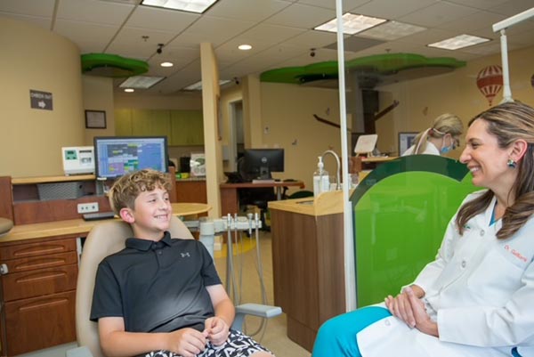 Dentist with patient - Patient is a young boy in the chair, smiling back at the female dentist.