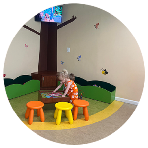 Young children happily playing in a children's play area with small stools and toys.