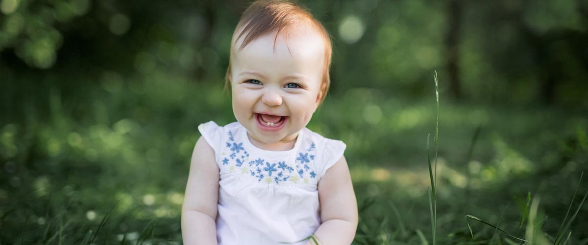 Very young child with two small bottom front teeth, smiling from ear to ear.